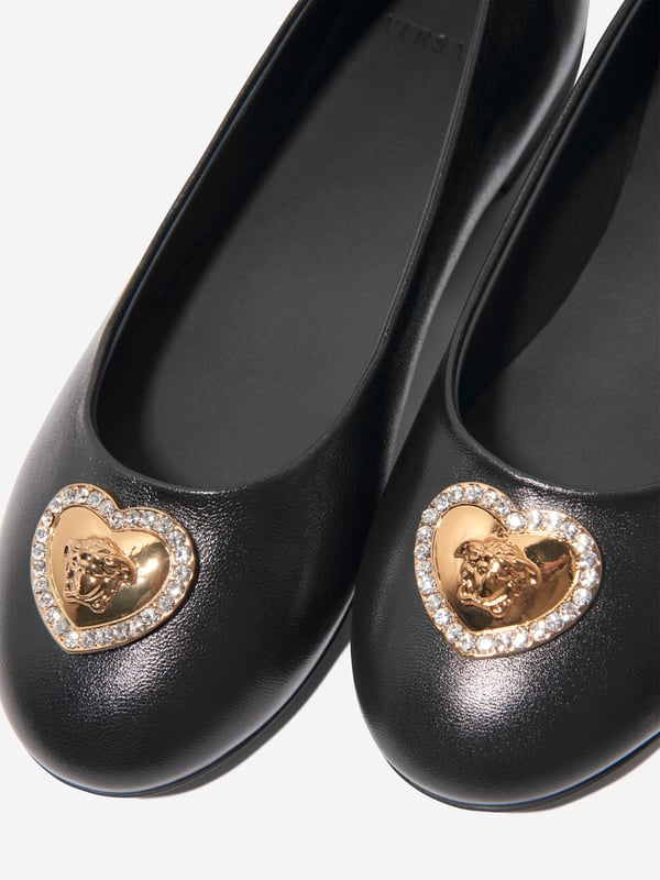 Versace encapsulate their daring aesthetics with a bold unapologetic attitude. These girls heart logo pumps on black are reflective of the luxury Italian label's experimentative approach. Crafted in refined materials, they feature crystal-embellished, heart-shaped Medusa charms at the toes. Both cute and stylish, they will be her favourite to wear at school and other weekend occasions.  Made In Italy Heart Medusa Charm Crystal Detail Round Toe 72% Viscose, 28% Silk 100% Calf Leather 100% Rubber