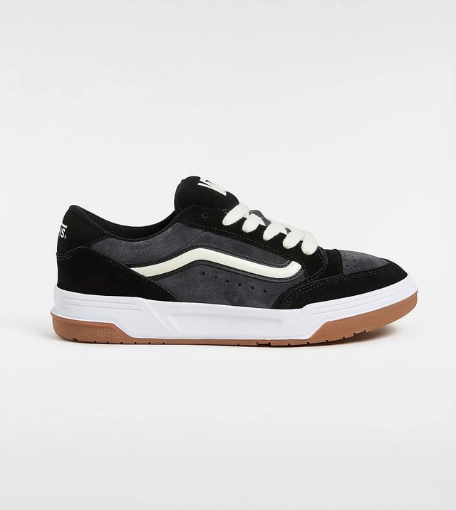 Vans Hylane Schwarze Turnschuhe Tauchen Sie mit Sneakers im Retro-Stil ein, die über Wildleder- und Synthetik-Obermaterialien für Strapazierfähigkeit und Komfort verfügen. Gestaltet mit einer 3D-gelackten Seitenstreife und bestickten Logos für einen kühnen, auffälligen Look. Die klobige Silhouette und die gepolsterte Skater-Zunge vermitteln eine nostalgische Atmosphäre, während die klassische Gummiprofilsohle für zuverlässigen Halt und Traktion sorgt.