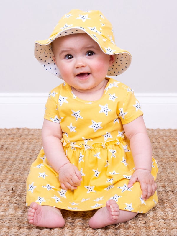 95% organic cotton 5% elastane | Proud to be certified to the Global Organic Textile Standard (GOTS) | Super starfish all-over print | Soft butter yellow | Single jersey with a little bit of stretch (180-190 gsm) | Combined bodysuit and dress | Popper crotch and shoulder opening | Short sleeved | Round neck | Made in Turkey | Machine washable at 40 degrees, or at 30 degrees to be kinder to the planet