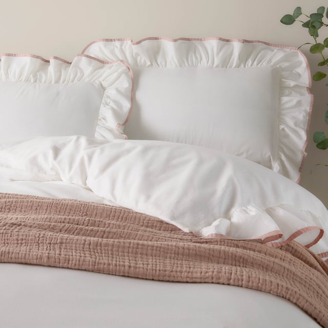 Transform your bedroom into a serene retreat with the Blousey Pillowcases. Crafted from 100% cotton sateen with a luxurious 180 thread count, these pillowcases are as soft as they are stylish. A subtle yet elegant ruffled trim, accentuated by a delicate piped detail, adds a touch of timeless sophistication to your bedding ensemble. Perfect for layering with textured throws or cushions, they create an effortlessly cosy yet refined aesthetic that complements both minimalist and relaxed interiors. These pillowcases not only enhance your bedroom’s visual appeal but also provide a breathable, comfortable surface for restful sleep.