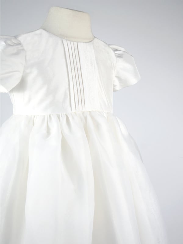 Perfect for Flower Girls, Bridesmaids or Special occasion!
'Dolly' evolved from one of our most popular dresses.

It has been beautifully re-designed to include our pin tuck detailed front, button back and gorgeous puffed sleeves to create the prettiest of dresses that is as comfortable as it is fun. Team it with a sash, ribbon or flower in any colour to match your colour scheme.

You'll find all our dresses are lined in cotton lawn for extra softness and perfect for sensitive skin.

The dress will arrive with you on a Satin padded hanger and covered in one of our Heritage garment protector bags for safe keeping.

Outer - 100% Mock Silk polyester fabric and trims

Lining - 100% cotton

Dry Clean or Hand Wash