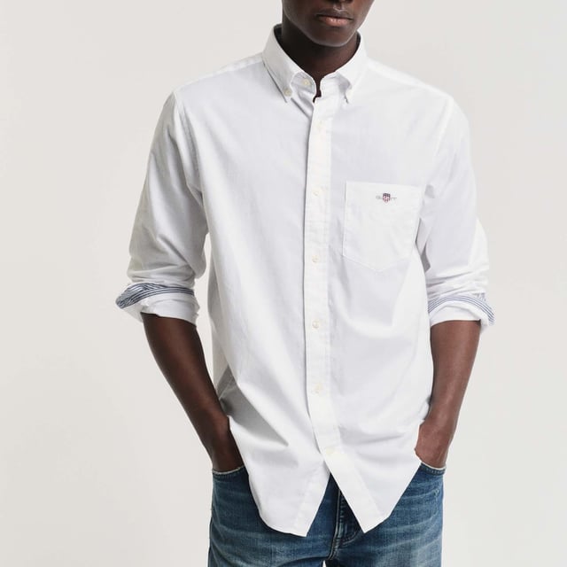 The shirt is made from durable poplin fabric  and is a true classic for your preppy wardrobe. Featuring a rounded hem and an embroidered 1980s-style GANT crest graphic on the chest pocket.