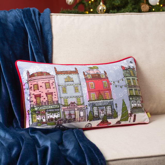 Inspired by traditional, heritage shops, the Christmas Spirit cushion is adorned with Christmas décor and snow. The design features visual delights such as a chocolate box-style street scene, decorated trees and a car overloaded with presents. For more festive fun, the reverse is made with a sumptuous velvet in Santa Claus red. The perfect addition for the seasonal period!