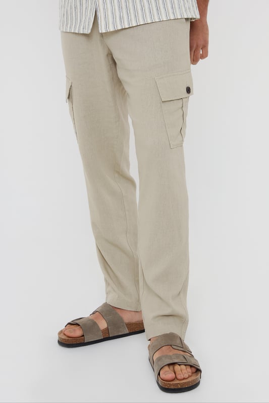 Upgrade your wardrobe with these linen blend cargo trousers from Threadbare. These linen mix cargos are the perfect blend of comfort and style, and with a part elasticated waistband with drawcords, they hit the laidback luxe trend with ease. Cut in a regular fit with a twin needle stitched hem, belt loops, mock horn button and zip fly closure. Linen-rich, these trousers will keep you cool and comfortable all day long, and have two side pockets, two back pockets, along with a button closure pocket on each leg. Team with a casual shirt to complete the look.