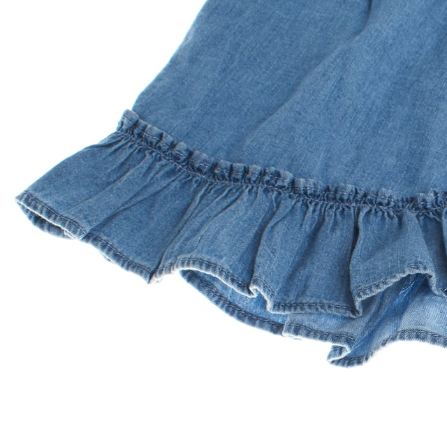 Sleeveless blouse for girls made of light denim fabric, ideal for warm days.

 It features adjustable thin straps and a gathered round neckline, which provide a delicate and fluid touch.

 The design includes a decorative ruffle at the hem, adding a feminine and casual touch.

 At the back, it features an elegant overlay with button closure, giving it a fun and dynamic look.

 Perfect to combine with shorts or skirts, this blouse is ideal for a casual and fresh look.
 Composition: 100% Cotton
 Care:
- Machine wash cold.
 - Use similar colors in the wash.
 - Avoid the use of bleaches.
 - Dry at low temperature in the dryer.
 - Iron at low temperature.
 - Do not dry clean.