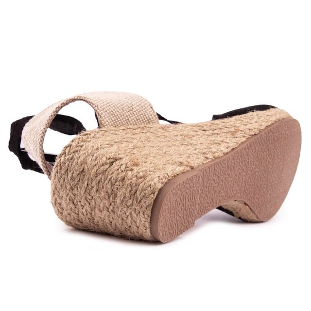 Dale un toque final a tu estilo veraniego con esta cómoda sandalia cuña que fusiona con un zapato de tacón de Solesister. El tacón de yute estilo alpargata se combina con una parte superior en negro y natural, mostrando finos tirantes alrededor del tobillo y un ajuste más amplio. La adición perfecta a tus looks para climas cálidos.