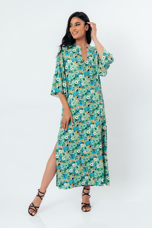 Deze zomerjurk in kaftanstijl met bloemenprint is gemaakt van geweven viscose. Het heeft een mandarijnkraag en een V-halslijn. De mouwen zijn lang met ruches aan de manchetten. De zoom heeft grote zijsplitten. Deze jurk heeft een lang, los, recht silhouet.