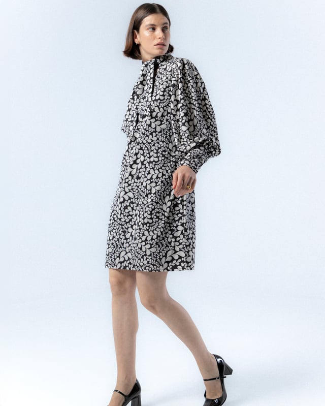 El vestido corto Paula en blanco y negro es sinónimo de elegancia, con este vestido de manga abullonada elevarás tu estilo invernal. Además, su pañuelo a juego te permitirá crear distintos looks con este vestido blanco y negro.
 
 
 
 Vestido corto con cuello pico.
 
 Manga larga acabada con puño con cremallera.
 
 Cierre lateral con cremallera oculta en costura.
 
 Con pañuelo confeccionado en mismo tejido y cara interna con tejido color negro.
 
 Tejido estampado blanco y negro con detalles de foil dorado.
