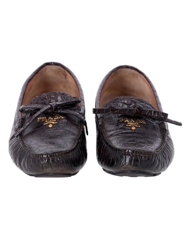 VINTAGE, RRP WIE NEU  
Tauchen Sie ein in die Eleganz mit den Prada Bow Loafers aus braunem, krokodilgeprägtem Leder. Diese Slipper sind eine raffinierte und zeitlose Wahl, die mit einer luxuriösen, krokodilgeprägten Textur und einem femininem Schleifchen-Detail versehen sind. Der reiche Braunton verleiht Wärme und Vielseitigkeit, perfekt um vom Tag in die Nacht zu wechseln.  
*mit Box  

Prada Bow Loafers aus braunem krokodilgeprägtem Leder  
Material: Leder  
Farbe: Braun  
Größe: EU37.5  
Zustand: Sehr gut  
Abnutzungserscheinungen: Mäßiger Gebrauch überall  
SKU: 365502