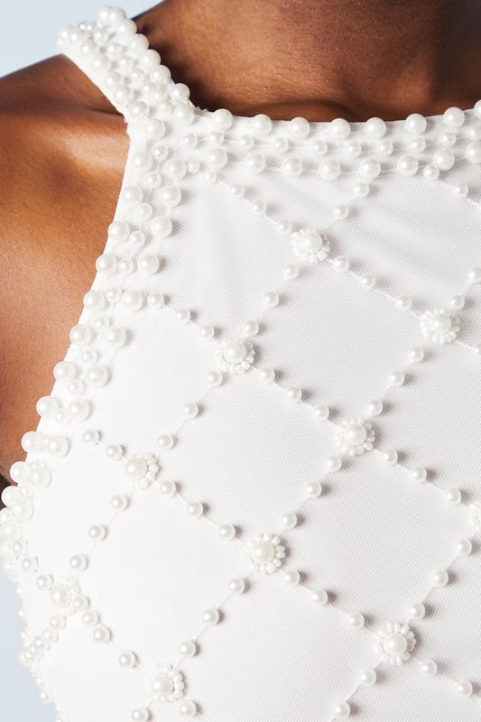 Stunning geometric pearl embellishment
        Elegant halterneck design
        Figure-flattering column silhouette
        Sophisticated midi length
        Delicate hand-stitched detailing
    
    Make a lasting impression on your special day with this exquisite bridal dress from Coast. The intricate geometric pattern adorned with pearls creates a mesmerising visual effect, perfect for the modern bride who desires a touch of glamour. The halterneck style elegantly frames the dcolletage, while the column silhouette gracefully skims your curves. Pair with strappy heels and pearl drop earrings for a cohesive bridal look. This dress is versatile enough for various wedding venues, from a chic city celebration to a romantic beach ceremony. The midi length offers practicality without compromising on style, allowing you to move with ease during your first dance and beyond. This Coast creation is a testament to timeless elegance, ensuring you feel confident and radiant as you embark on your new chapter.