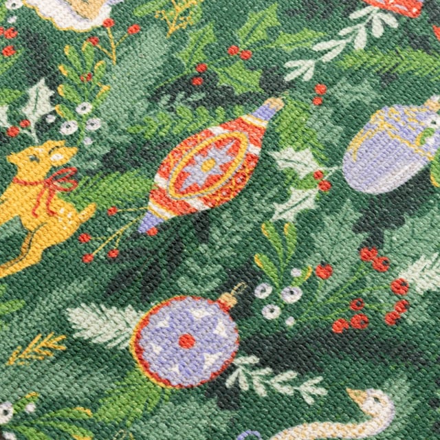 Get into the Christmas spirit with this wonderfully festive table runner. Featuring a digital printed design on woven polyester fabric of Christmas foliage and traditional tree decorations, including vintage baubles, candles and even a swan in vivid seasonal colours. This beautiful table runner will transform and add some instant seasonal cheer to your Christmas dining table.