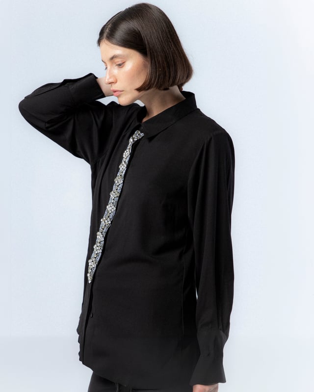 Atrévete con la camisa negra de pedrería Lucía. Con el detalle de las pedrería en el centro de la prenda, la camisa Lucía se convierte en tu mayor aliada para looks de noche este invierno.
 
 
 
 Camisa con cuello solapa.
 
 Detalle de pedrería plata en tapete.
 
 Manga larga acabada con puño.
 
 Forro de satén por separado.