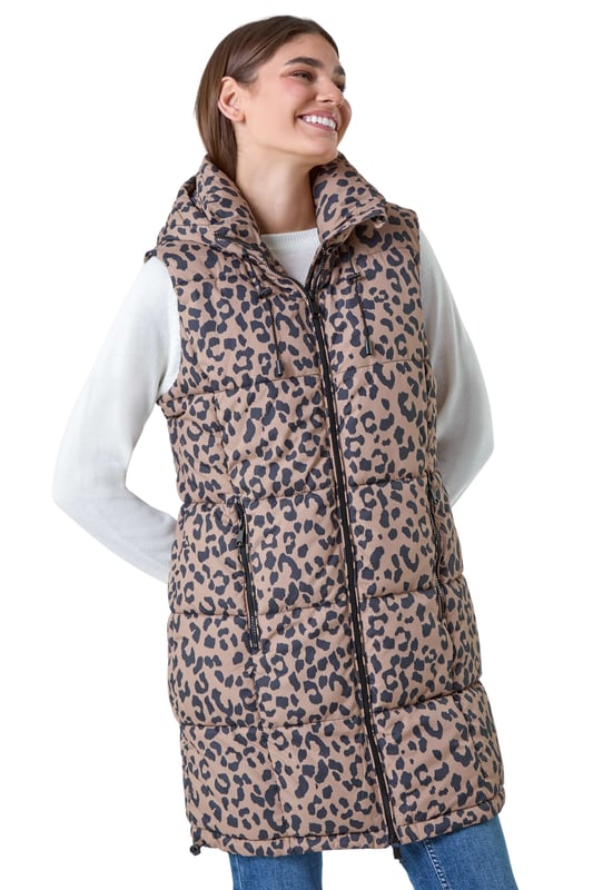 Animal Print Longline Hooded Gilet from Roman. Gilets are the perfect option for the transitional seasons, providing just the right amount of warmth for unpredictable weather. Cut from a woven fabric this gilet features a cosy funnel neck and a front zip fastening for a secure fit. A practical hood is finished with a drawstring cord for an adjustable fit, while zipped pockets provide space for your everyday essentials. Adorned in a fun animal print this piece is padded for extra warmth. Pair with relaxed denim and knitwear with either boots and trainers for trendy everyday style!