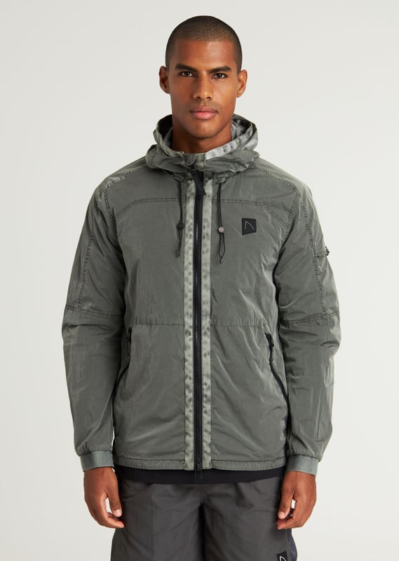 The Ortega is a regular fit summer jacket made from garment dyed polyamide for a unique color. It features a 2-way zip with tonal webbing tape, 2 side pockets, and an interior pocket with a zipper. Signature details include the CHASIN' comma badge and branded cord stoppers. The lining is made from polyester mesh.