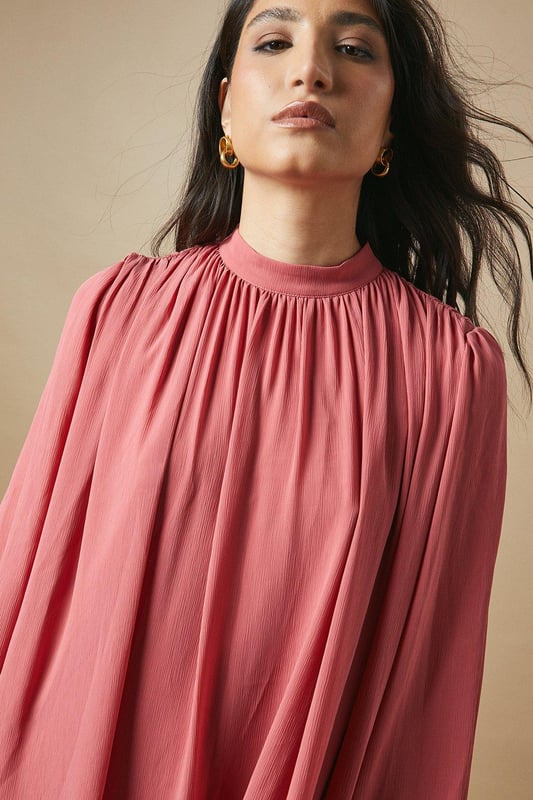 Elegant high neck design for a sophisticated look
        Flowy chiffon fabric creates a graceful silhouette
        Voluminous balloon sleeves add a romantic touch
        Tiered ruffle hem for playful movement
        Versatile mini length suitable for various occasions
    
    This charming high neck chiffon mini dress from Oasis is the epitome of feminine allure. The airy chiffon fabric drapes beautifully, creating a flattering and comfortable fit for all-day wear. The dress features eye-catching balloon sleeves that add a touch of drama to your ensemble, while the tiered ruffle hem introduces a playful element to the overall design. Perfect for casual daytime events, this dress can be styled effortlessly for family gatherings or weekend brunches. Pair it with ankle boots and a leather jacket for an edgy contrast, or opt for ballet flats and delicate jewellery for a softer look. The versatile nature of this dress allows for easy transition from day to night - simply swap your accessories to suit the occasion. Embrace your girly side and make a statement in this delightful Oasis creation.
