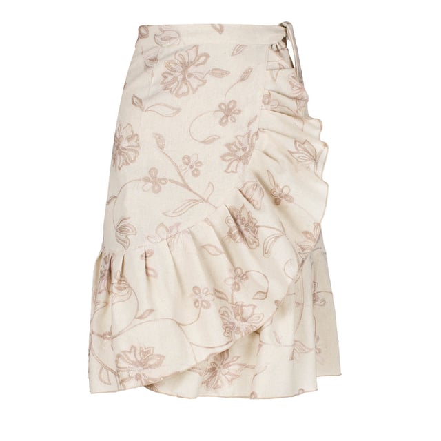Esta falda cruzada floral de color crudo está confeccionada en un tejido de mezcla de lino y bordada con un hilo bicolor en crudo y beige. La falda se abrocha con una corbata de 4,5 cm del mismo tejido que pasa a través de un agujero en la costura lateral, justo debajo de la cintura. La falda tiene un ribete de volantes de 26 cm por todas partes. Tiene un estilo sutil con una silueta de línea A y llega hasta la rodilla.