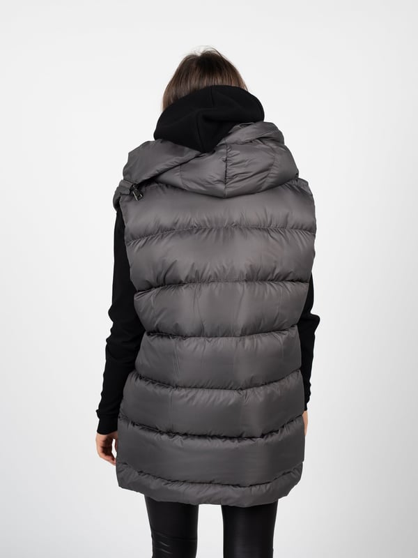 El color uniforme de nuestra chaqueta es la solución ideal para aquellos que valoran la elegancia y la simplicidad en sus estilismos diarios, además de la facilidad para combinarla con otros elementos del vestuario.

El diseño más largo proporciona no solo un confort excepcional y calidez en los días más fríos, sino que también añade a la silueta una apariencia esbelta y un acabado clásico, perfecto tanto para el uso diario como para ocasiones más formales.

El gorro, por su parte, es un agregado práctico que protege contra las condiciones climáticas adversas, y al mismo tiempo le da a la chaqueta un carácter moderno y deportivo.

Cerrada con cremallera y botones, la chaqueta sin mangas ofrece protección adicional contra el viento y el frío, además de permitir un rápido y cómodo ponerse y quitarse, lo cual es extremadamente práctico en el uso diario.

Fabricada en Italia, lo que garantiza la más alta calidad de los materiales y una fabricación precisa, característica de la artesanía italiana, famosa por su atención a cada detalle y excepcional habilidad artesanal.