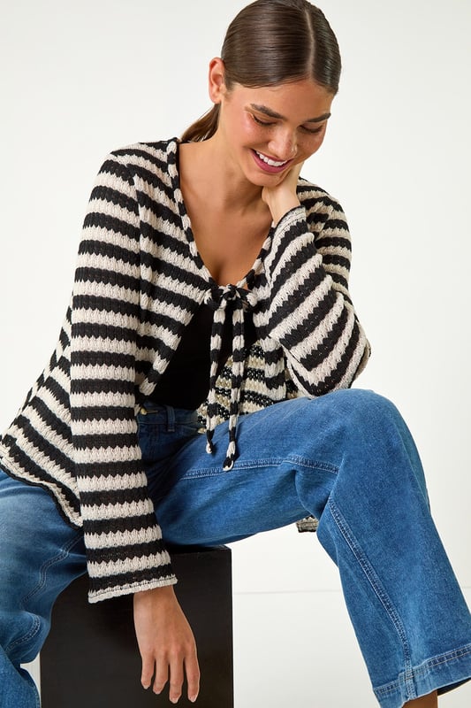 Striped Print Tie Detail Cardigan from Roman. Stay warm and stylish this Autumn with our stripe print cardigan. Crafted from a cosy pointelle knit fabric, this cardi features a trendy tie front fastening, perfect for layering on those cooler days. The hip-length design and long sleeves ensure a comfortable and flattering fit. Pair with jeans and ankle boots for a chic and effortless daytime style.