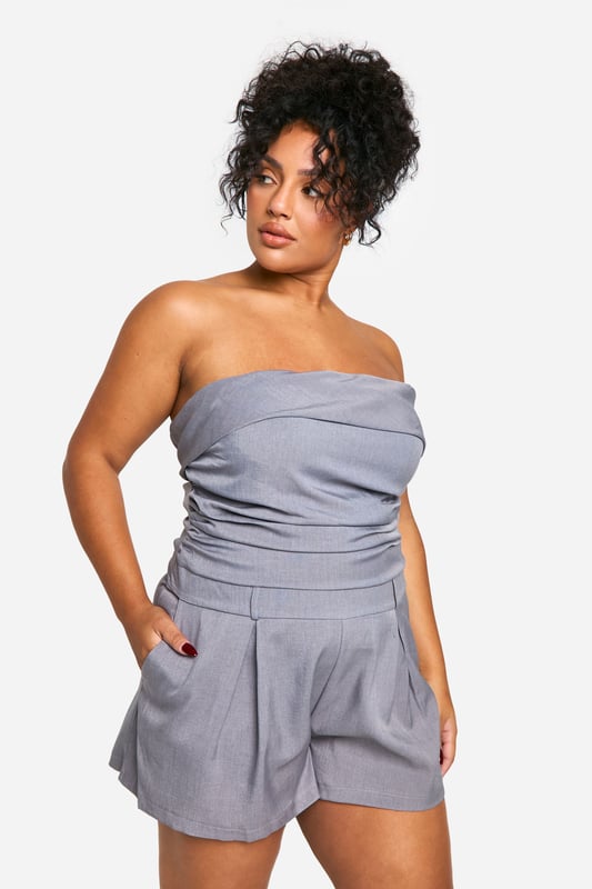 Chic bandeau neckline for a sleek, strapless look
        Flattering ruched detailing accentuates curves
        Versatile playsuit design perfect for day-to-night wear
        Comfortable elasticated waistband for a secure fit
        Practical side pockets add functionality to style
    
    Embrace effortless elegance with this stunning plus-size bandeau playsuit from Boohoo. The ruched detailing adds a touch of sophistication while flattering your curves in all the right places. Perfect for transitioning from day to night, this versatile piece can be dressed up or down with ease. For a chic daytime look, pair with flat sandals and oversized sunglasses. When the sun sets, swap your flats for strappy heels and add statement earrings to take your outfit from desk to dinner. The playsuit's comfortable fit and practical pockets make it ideal for various occasions, from casual brunches to evening cocktails. Layer with a cropped jacket for cooler evenings or rock it solo to show off its sleek silhouette. With its blend of style and comfort, this playsuit is sure to become a go-to favourite in your wardrobe.