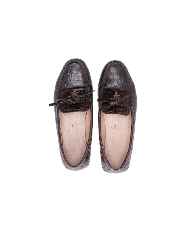 VINTAGE, RRP WIE NEU  
Tauchen Sie ein in die Eleganz mit den Prada Bow Loafers aus braunem, krokodilgeprägtem Leder. Diese Slipper sind eine raffinierte und zeitlose Wahl, die mit einer luxuriösen, krokodilgeprägten Textur und einem femininem Schleifchen-Detail versehen sind. Der reiche Braunton verleiht Wärme und Vielseitigkeit, perfekt um vom Tag in die Nacht zu wechseln.  
*mit Box  

Prada Bow Loafers aus braunem krokodilgeprägtem Leder  
Material: Leder  
Farbe: Braun  
Größe: EU37.5  
Zustand: Sehr gut  
Abnutzungserscheinungen: Mäßiger Gebrauch überall  
SKU: 365502