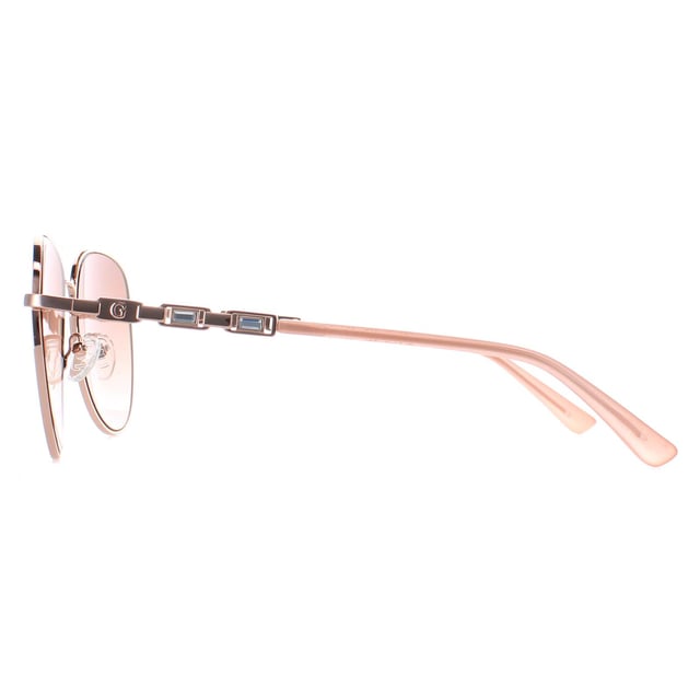 Guess Aviator Womens Shiny Rose Gold Brown Gradient GF6143  Sunglasses are a glamorous aviator frame, exuding a sense of timeless elegance. The frame is crafted from high-quality metal, known for its durability and lightweight feel, ensuring long-lasting comfort throughout the day. The slender temples feature the Guess logo for authenticity.