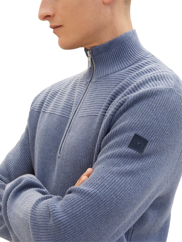 Dieser Tom Tailor Troyer-Pullover für Herren ist ein echter Hingucker. Aus hochwertigen Materialien gefertigt, ist er äußerst angenehm zu tragen. Er hat lange Ärmel und einen Stehkragen, der durch die Strickrichtung abgesetzt ist. Der Troyerkragen verleiht dem Pullover einen eleganten und doch lässigen Look. Er hat einen halben Reißverschluss, der das An- und Ausziehen erleichtert. Auf dem oberen Ärmel befindet sich ein Logo-Badge, das die Marke Tom Tailor repräsentiert und Ihre Persönlichkeit unterstreicht. Das Besondere an dieser Strickjacke ist die horizontale Struktur im oberen Drittel, die dem Strickpulli einen interessanten und dynamischen Charakter verleiht. Die unteren zwei Drittel sind ohne Struktur vertikal gestrickt und heben sich gut ab. Bündchen und Saum sind gerippt und sorgen für einen perfekten Sitz. Eine normale Passform, die sich jeder Körperform anpasst. Dieser Strickpulli ist in verschiedenen Farben und Größen erhältlich und kann zu jedem Anlass getragen werden. Ob mit Hemd, T-Shirt oder Jeans kombiniert, dieser Troyer ist ein echter Allrounder. Bestellen Sie jetzt und überzeugen Sie sich von seiner Qualität und seinem Stil.