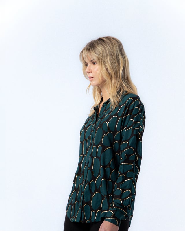 La camisa estampada Victoria te enamorará con su elegante color azul petróleo. Déjate envolver por el diseño sofisticado de la camisa Victoria.
 
 
 
 Blusa holgada con cuello solapa.
 
 Manga larga.
 
 Cierre frontal con botones.
 
 Detalle de tapete con botones en espalda.
 
 Tejido viscosa.
 
 Estampado Abstracto con detalles de foil dorado.