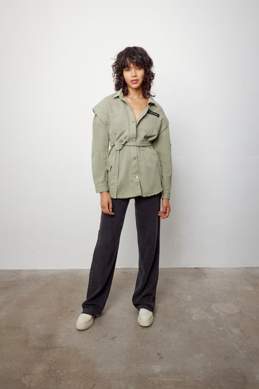 This khaki shirt with removable belt has military badges on the chest and sleeve and two patch pockets on the chest. It has a shirt collar, long sleeves, details at the shoulders and a ripped effect on the bottom. Button fastening.