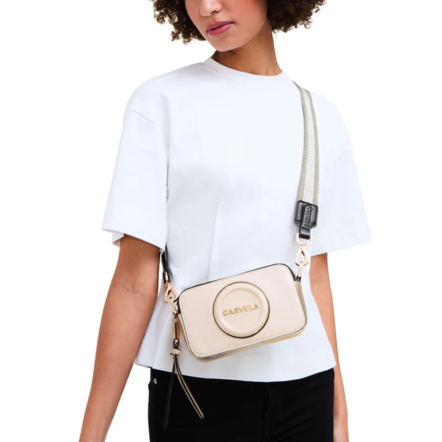 This Carvela Mini Roma Circle cross body bag features a bone exterior with round embossed branding on the front. There is branded gold hardware across the bag. Dimensions: 11cm (H), 18cm (L), 5cm (D). Strap length: 126cm.