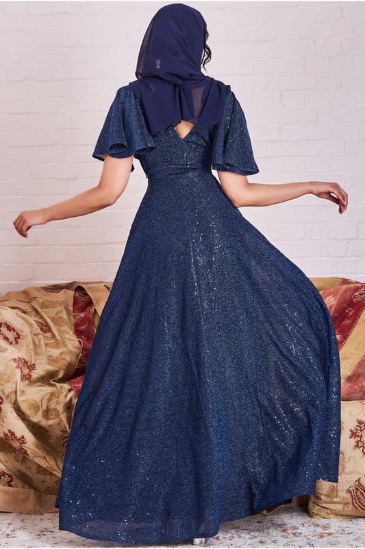 *PLEASE NOTE SCARF IS NOT INCLUDED*The Sequin Lurex Flutter Sleeve Maxi Dress from Goddiva is the dress for you! This dress is perfect for any occasion, from daytime events to evening soirees, and is ideal for bridesmaids or mothers of the bride (or groom). With its wrap style v-neckline and flutter sleeves, this dress has a feminine and elegant touch. The a-line skirt complements the flutter sleeves perfectly, creating a silhouette that is both flattering and modest. The sequin and lurex finish adds an extra touch of glamour and sparkle to this navy dress, making it perfect for any formal event. This dress is also a great choice for modest fashion, making it perfect for Eid celebrations or other events where modest dress is preferred. The striking and sparkly effect of the sequins and lurex fabric creates a bold yet elegant look that is sure to turn heads. Pair this maxi dress with a scarf, strappy sandals and a statement necklace to complete the look.