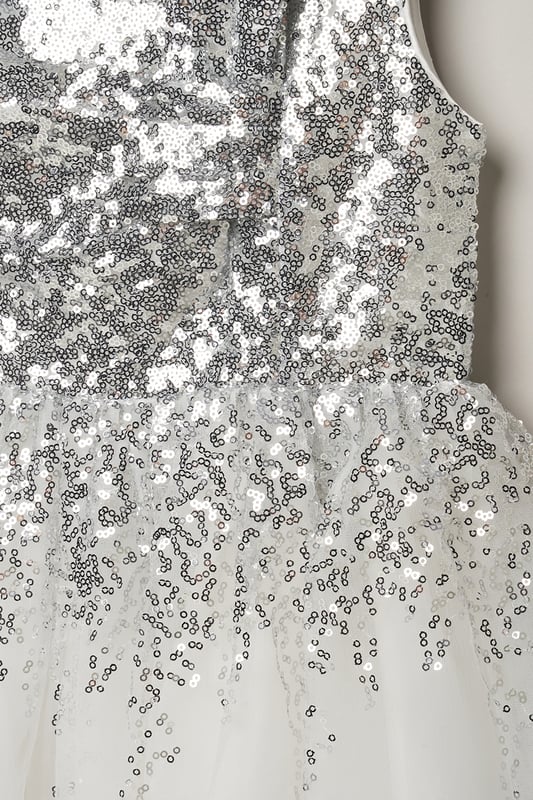 Step into magic with this sequin waterfall dress from Luna Moon by Miss, featuring a stunning large bow at the back. Watch her dazzle in this mesmerizing ensemble, effortlessly transitioning from shimmering sequins to a flowing tulle skirt. Perfect for special occasions, this dress promises to charm wherever she goes. This dress is the perfect blend of sparkle and sophistication.