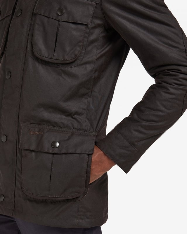 Barbour Corbridge Wax Jacket
The Corbridge is a rugged utility-style men's waxed jacket updated with a contemporary engineered fit. With winter in mind, this multi-functional jacket is constructed in Barbour's hardy 6oz Sylkoil waxed cotton with a comfortable, lightweight Nylon lining quilted to 50g wadding, for additional warmth. The corduroy-lined funnel collar features an integral Nylon hood complete with adjustable toggles for a perfect fit, offering wet-weather defence when needed but easily stowed away in the collar on dry days. Built to offer comfort and protection to those who are active outdoors in any weather, the Corbridge benefits from adjustable cuffs, a robust two-way zip, a storm fly front with stud fastenings and an action back. The classic four-pocket detail adds a stylish, practical feature that keeps essentials safe and hands free. Available in a choice of three versatile colours. As this is a slim fitting jacket, we would advise purchasing the next size up than you would normally choose.

Tailored Fit
Barbour tonal embroidery to left pocket
Outer: 100% cotton (waxed)
Inner: 100% polyamide
6oz waxed cotton
Do not wash
Sponge clean only
Back length: 78.8cm - 83cm

MWX0340