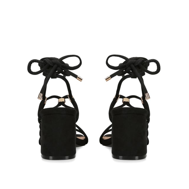 The KG Kurt Geiger Raya heel features a black microsuede upper with gold and KG Kurt Geiger stud hoops connecting the straps. The heel is a classic high block style. Heel height: 70mm.