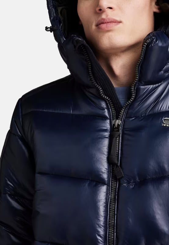 G Star Raw Jacke Diese Steppjacke für Herren ist ideal für kalte Tage. Die Jacke hat ein schönes warmes Futter und ist mit einer wasserabweisenden Ausrüstung versehen. Es hat eine reguläre Passform, die genügend Bewegungsfreiheit und hohen Tragekomfort bietet. Durch Kordelzüge in der Taille lässt sich die Weite regulieren. Die Kapuze lässt sich hoch schließen und mit einem Kordelzug verstellen, um den Hals vor Wind und Kälte zu schützen. Außerdem verfügt es über einen Schirm, der per Druckknopf befestigt werden kann. Geschlossen wird die Jacke mit einem durchgehenden Reißverschluss, der mit einem Windschutz versehen ist. Die elastischen Bündchen verhindern das Eindringen von Kälte und ein Verrutschen der Ärmel. In den beiden seitlichen Paspeltaschen mit Druckknöpfen kannst du deine Hände wärmen oder Kleinigkeiten verstauen. Das dezente Label auf der Brust rundet das Design ab.