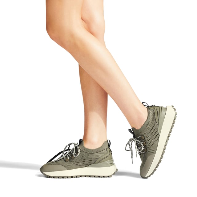 The KG Kurt Geiger Lux is a knitted style sneaker in khaki. The tubular style laces tie at the front whilst there are black branded tabs at the front and back of the ankle.