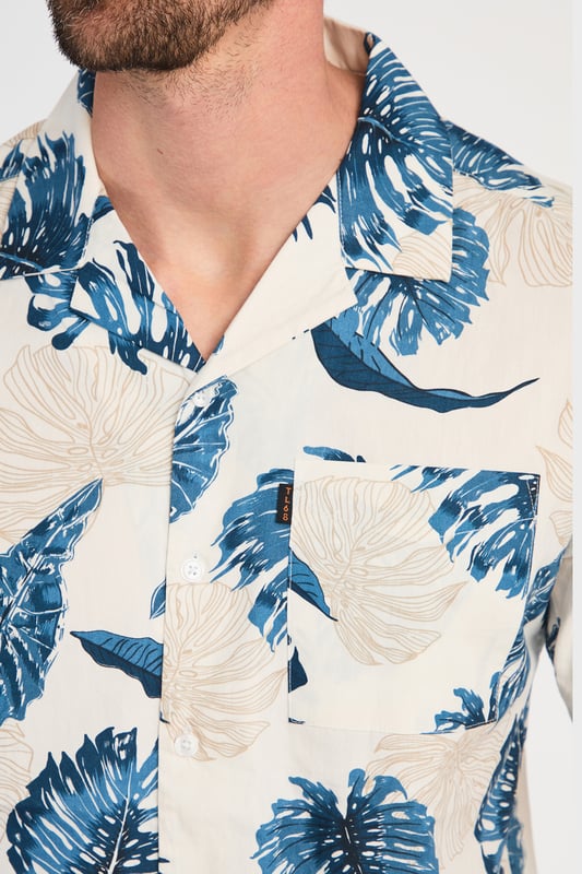 Blue Cotton Printed Poplin Short Sleeve Shirt This 100% cotton poplin leaf-printed shirt by Tokyo Laundry offers a stylish, tropical vibe with a chest pocket for added convenience. Lightweight and breathable, it’s perfect for warm weather. Pair it with chino shorts or linen trousers for a relaxed yet refined look. A must-have addition to your summer wardrobe.