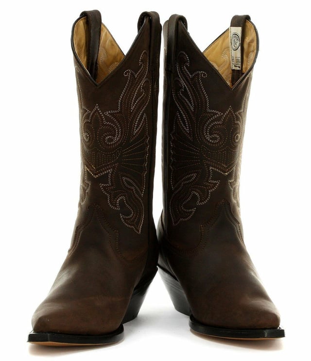 The Grinders Buffalo is a quality, hard wearing all leather western cowboy boot. This style features a brown oiled upper which is abrasion resistant for longer wear and sports a colour contrasting stitched detailed pattern on the shaft. This boot is given an iconic Western style with introductions such as a pointed toe and 2.25-inch stacked Cuban heel and is made comfortable using a full leather lining and insole. The branded genuine leather sole unit provides greater durability and the two side pull on loops makes the boots easier to put on, all of which add to the comfort and practicality of this stylish luxury Buffalo boot. • Goodyear Welted sole • Leather upper with detailed stitched design • Soft Leather lining • Stacked 2.25” Cuban heels • Leather Soles • Made in Mexico