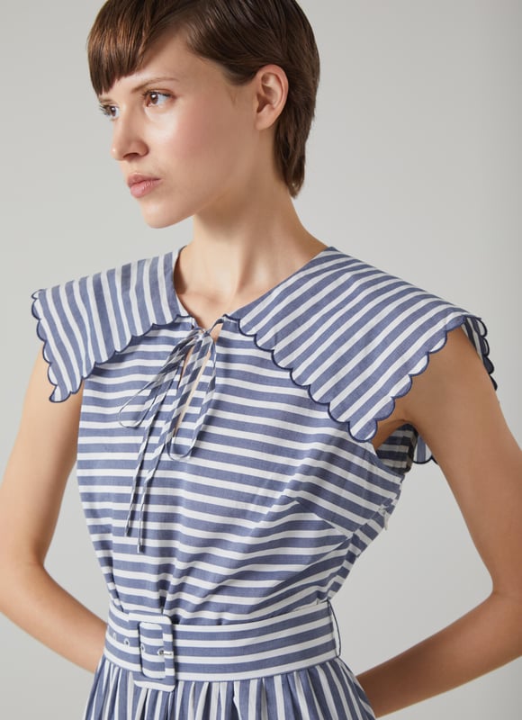 A chic sun dress which takes design cues from sailor style, beautiful Beau is destined for glamorous destinations. It's crafted from blue and cream striped cool cotton, and has a wide scalloped edge collar with tie detail, a fabric-covered buckle belt and an A-line midi skirt. Wear it with a pair of leather sandals and a basket bag.