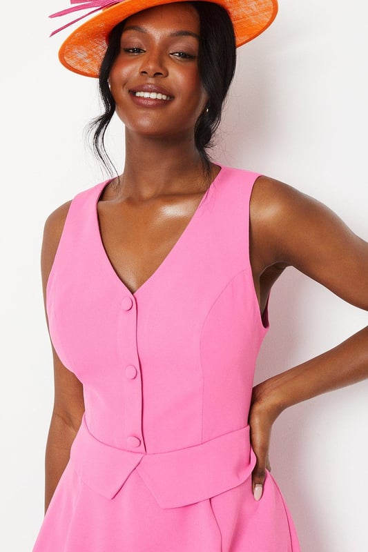 Elegant waistcoat-style bodice with button detailing
        Flattering V-neckline and sleeveless design
        Graceful midi length with a flowing drape skirt
        Sophisticated crepe fabric for a polished look
        Versatile silhouette suitable for various formal occasions
    
    Embody refined elegance with this captivating waistcoat midi dress. The structured bodice, adorned with delicate buttons, creates a striking contrast against the gracefully draped skirt, offering a harmonious blend of tailored sophistication and feminine fluidity. Perfect for weddings, race days, or any upscale event, this dress commands attention without compromising on comfort. Style it with strappy metallic heels and a coordinating fascinator for a quintessentially British look. For cooler evenings, drape a lightweight pashmina over your shoulders. Accessorise with understated jewellery to maintain the dress's clean lines and let its exquisite design take centre stage. This versatile piece transitions effortlessly from day to evening, making it a valuable addition to your occasion wear wardrobe.