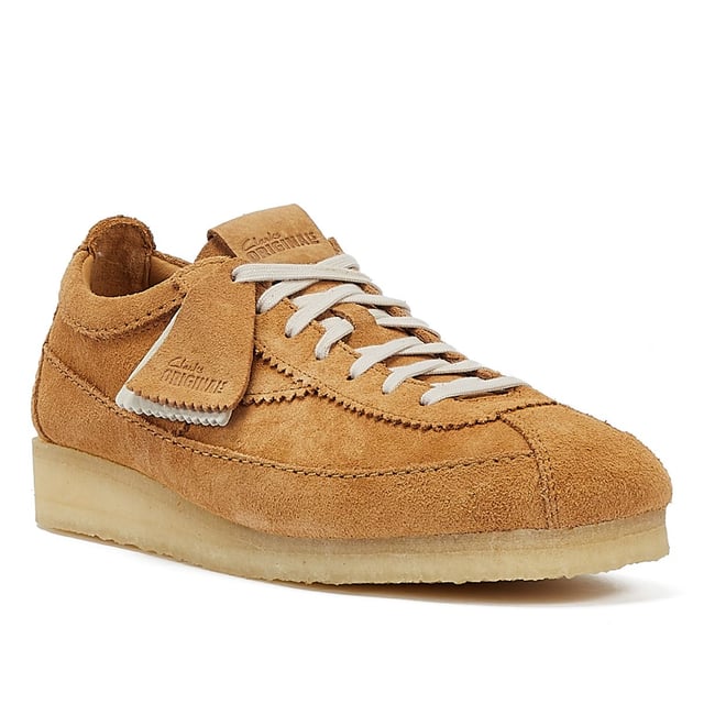 Introducing a premium mid-tan suede upper shoe with a sleek trainer silhouette, featuring tonal top-stitch details, complemented by a comfortable crepe sole. Finished with two Clarks Originals fobs.
