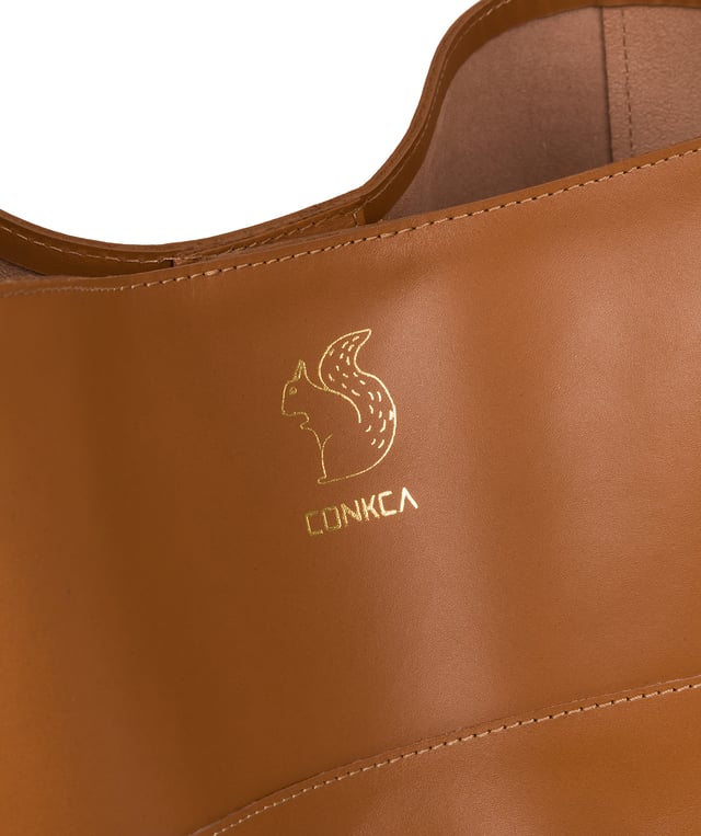 The 'Reynolds' shoulder bag from Conkca London's Camden Collection is that it is handcrafted from high-quality vegetable-tanned gold standard leather for a smooth and sophisticated finish. A magnetic clasp secures an open top and comes with an unlined, soft to the touch natural leather interior. Features a fuss-free, spacious central compartment for convenient storage. Fitted with a leather strap and is adorned with the inimitable Conkca squirrel charm and logo.