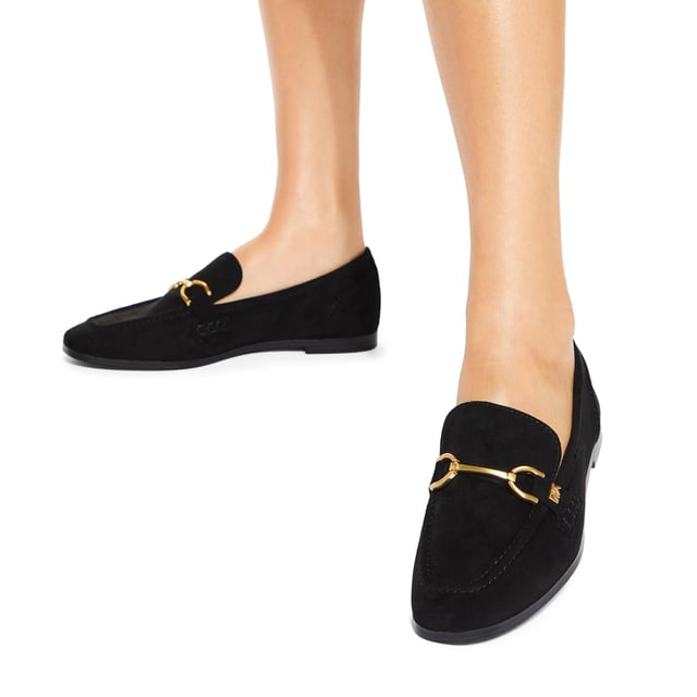 The KG Kurt Geiger Madeline is a black microsuede slip on loafer. There is an antiqued brass horse bit chain across the toe and small KG Kurt Geiger stud.
