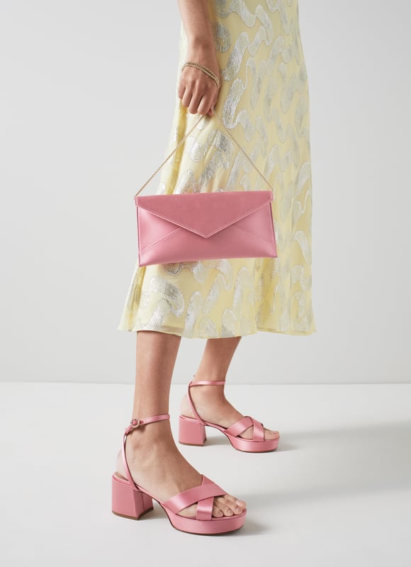 The Kendall clutch in the Royal Ascot x LKB collection is crafted in Spain from flamingo pink satin. It's a slim, rectangular shape with a V-point and press stud fastening, a removable gold chain shoulder strap and an inside slip pocket.