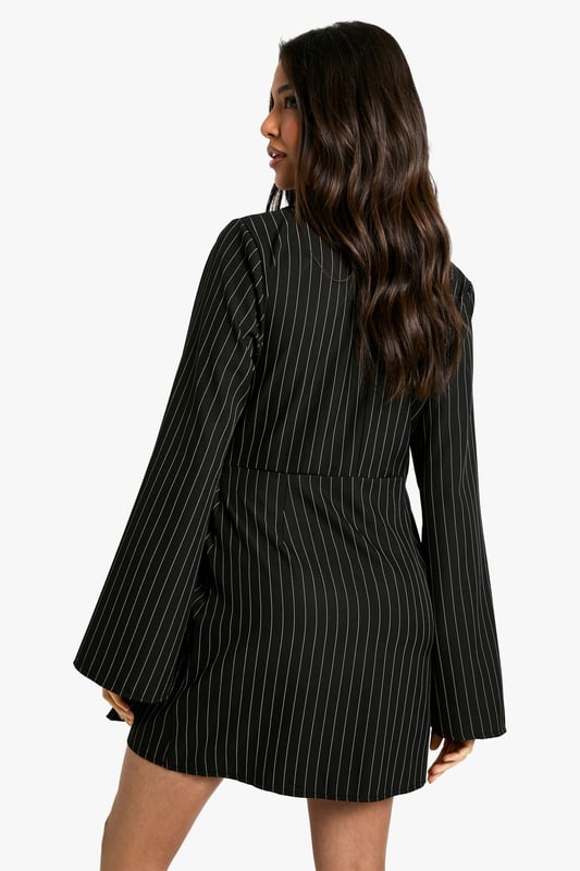 Striking pinstripe pattern for a bold, sophisticated look
        Wrap-style neckline adds a feminine touch
        Unique buckle detail at the waist for added interest
        Flared sleeves create a dramatic silhouette
        Versatile blazer dress design perfect for day-to-night transitions
    
    Make a statement in this eye-catching blazer dress from Boohoo. The pinstripe pattern adds a touch of classic sophistication, while the wrap-style neckline and buckle detail at the waist create a flattering, feminine silhouette. The flared sleeves add drama and movement to the overall look. Perfect for a night out with friends, this versatile piece can be dressed up or down. Pair it with strappy heels and statement earrings for a chic evening ensemble, or layer it over a turtleneck with ankle boots for a stylish daytime outfit. The blazer dress design offers endless styling possibilities, making it a must-have addition to your wardrobe. Whether you're heading to drinks at a trendy bar or dancing the night away at a club, this dress will ensure you stand out from the crowd.