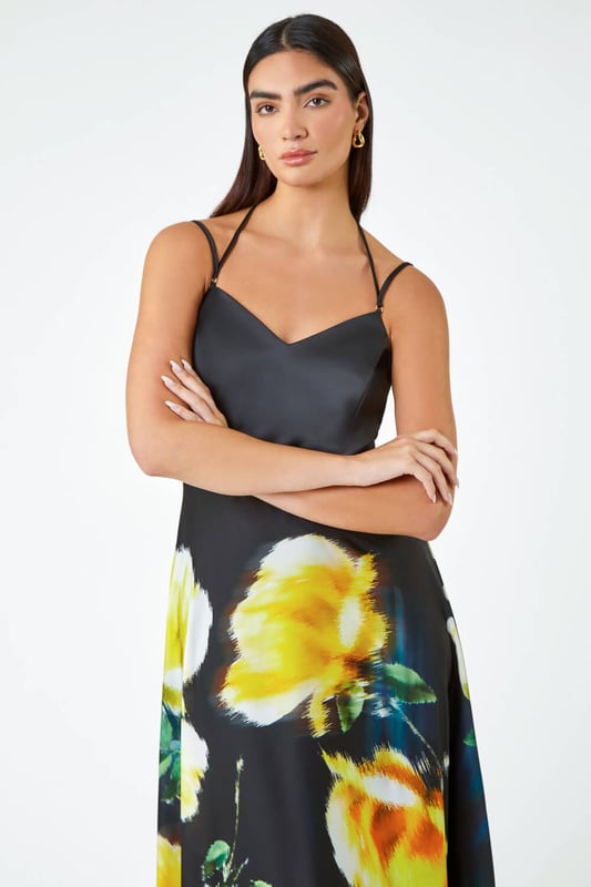 Luxe Floral Fit & Flare Maxi Dress from Roman. Feel glamorous in this luxurious floral maxi dress. Designed in a glamorous silhouette that cinches you in at the waist, this fit and flare gown features a strappy bodice with gold toggles. A flattering v-neckline and tie at the back adds more femininity to the dress, finishing at a floor sweeping full length. It has a romantic floral print, adjustable cami straps and concealed back zip to fasten. From Summer Weddings to formal dinners, this special occasion dress is sure to turn heads at any event this year.