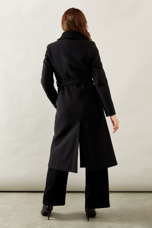 Elegant knitted collar for added sophistication
        Wrap design with button-through closure for versatile styling
        Long length offers maximum coverage and warmth
        Belted waist creates a flattering silhouette
        Functional side pockets for practicality
    
    This Wallis Knitted Collar Button Through Wrap Coat is the epitome of refined elegance. Perfect for the woman who appreciates sophistication without compromising on comfort, this coat is a versatile addition to any wardrobe. The wrap design allows for customisable fit, while the button-through closure adds a touch of classic charm. Style it over a sleek midi dress and pair with heeled boots for a polished look at formal events. For smart casual occasions, layer it over tailored trousers and a fine knit jumper, completing the ensemble with leather ankle boots. The long length and belted waist not only provide warmth but also create a striking silhouette that's sure to turn heads. Whether you're attending a business meeting or heading to a sophisticated dinner, this coat will ensure you look impeccably put-together while feeling effortlessly comfortable.