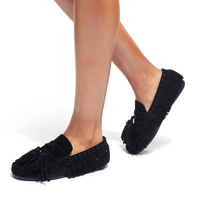 The Kurt Geiger Tassel Fringe Moccasin slip-on loafer features a black suede upper. There are tassel details across the upper as well as two statement tassels on the toe tongue, each with an black eagle head.