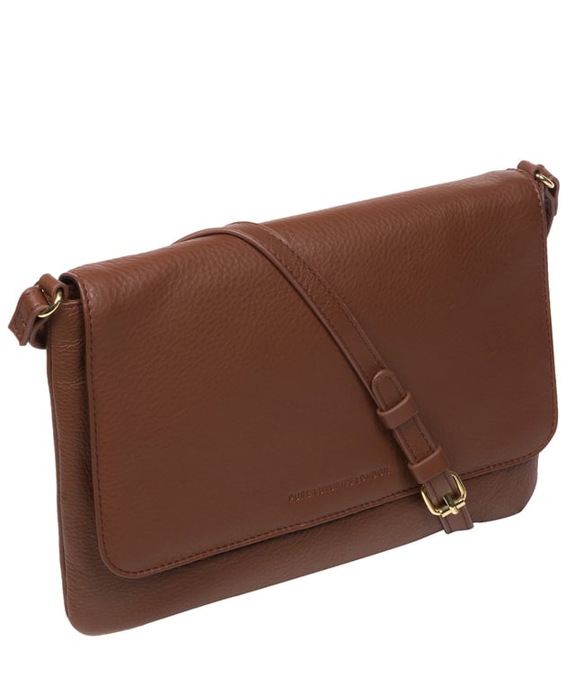 This stylish, sleek and spacious cross body bag from Pure Luxuries London's Marylebone Collection is a gem of a bag. The 'Ruby' features a fold-over top secured with a magnetic press-stud opens to reveal a 100% cotton lined interior and features three slip pockets concealed - ideal for all your essentials. The accessory is adorned with a slim and adjustable leather strap with a drop leather of 65cm. The design is finished with attractive gold-coloured metal fittings and zips which are a luxurious addition alongside the blind embossed Pure Luxuries logo which is a sophisticated finishing touch