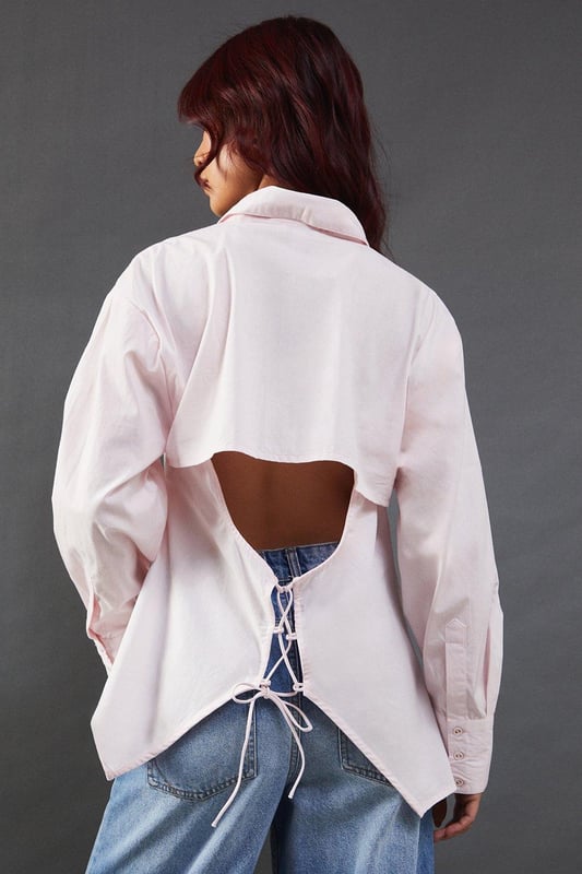 Striking open back design with tie detail
        Classic collared neckline for a polished look
        Long sleeves with button cuffs for versatility
        Relaxed fit through the body for comfort
        Crafted from breathable cotton poplin fabric
    
    Make a statement with this eye-catching poplin shirt from Warehouse. The open back design with delicate tie detail adds an unexpected twist to a classic silhouette, perfect for those who want to inject a bit of edge into their wardrobe. The relaxed fit and breathable cotton fabric ensure all-day comfort, while the collared neckline maintains a smart appearance. Style this versatile piece with your favourite denim for a casual daytime look, or dress it up with tailored trousers for a chic ensemble suitable for family gatherings or brunch with friends. The long sleeves can be rolled up for a more relaxed vibe, making this shirt adaptable for various occasions. Pair with flat sandals or trainers to complete your effortlessly cool outfit.