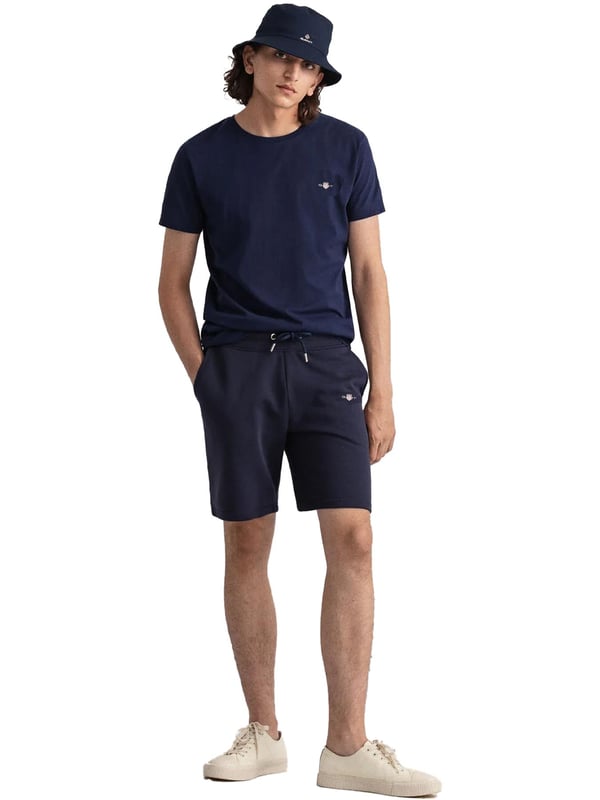 Gant introduces a mens t-shirt and shorts set with a small-scale embroidered shield graphic on the chest. Made of soft cotton and featuring a ribbed neckline, this tee showcases the iconic GANT logo. Crafted for everyday wear, the regular-fit tee is both comfortable and sustainable with Better Cotton. The included sweat shorts, also made of soft cotton blend, feature a ribbed waistband, three pockets, and a drawstring waist. The shorts are adorned with a small-scale embroidered shield graphic.